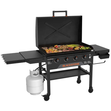 Blackstone 36” propane griddle cooking vegetables, meats, and skewers on large flat top grilling surface with open lid.