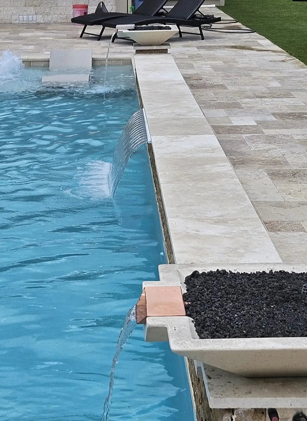 Travertine TessaRai Square Fire/Water Bowl Kit with copper scupper spillway beside luxury pool and sun shelf