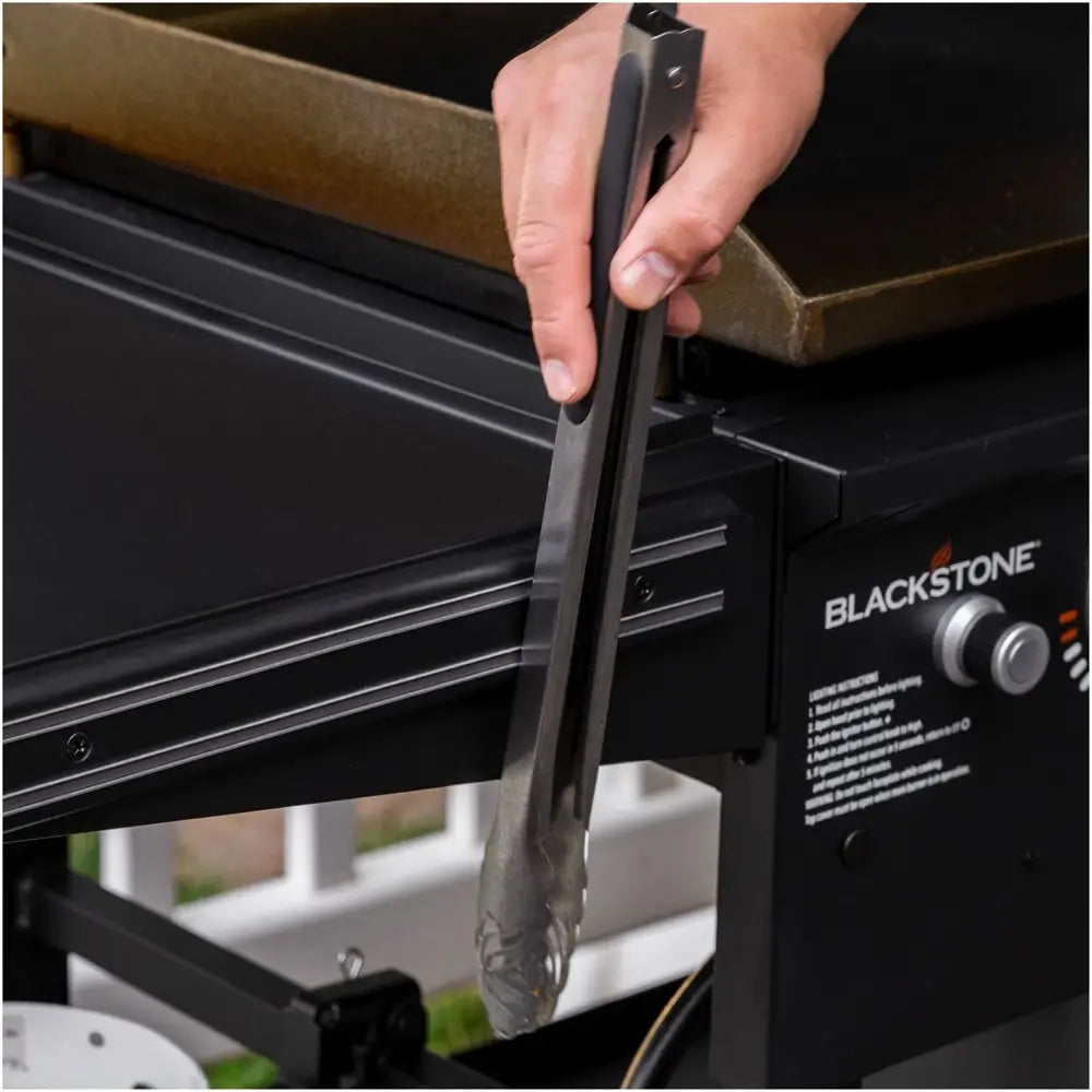 lose-up of magnetic tool strip on Blackstone griddle holding stainless steel grill tongs