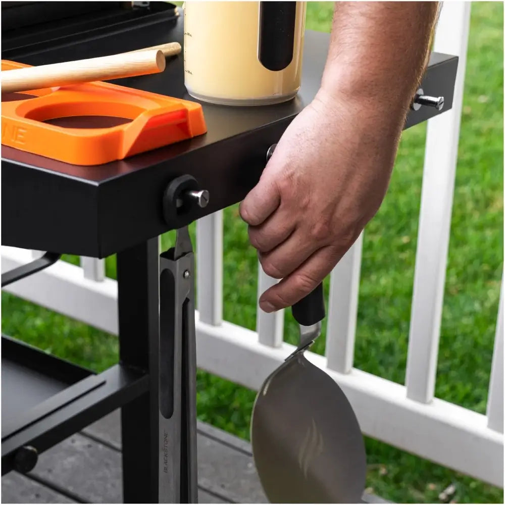 Tool hooks on right side shelf of Blackstone griddle holding spatula and tongs