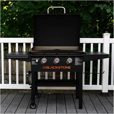Blackstone 28" griddle with hood set up on deck with open lid and triple burner controls in view