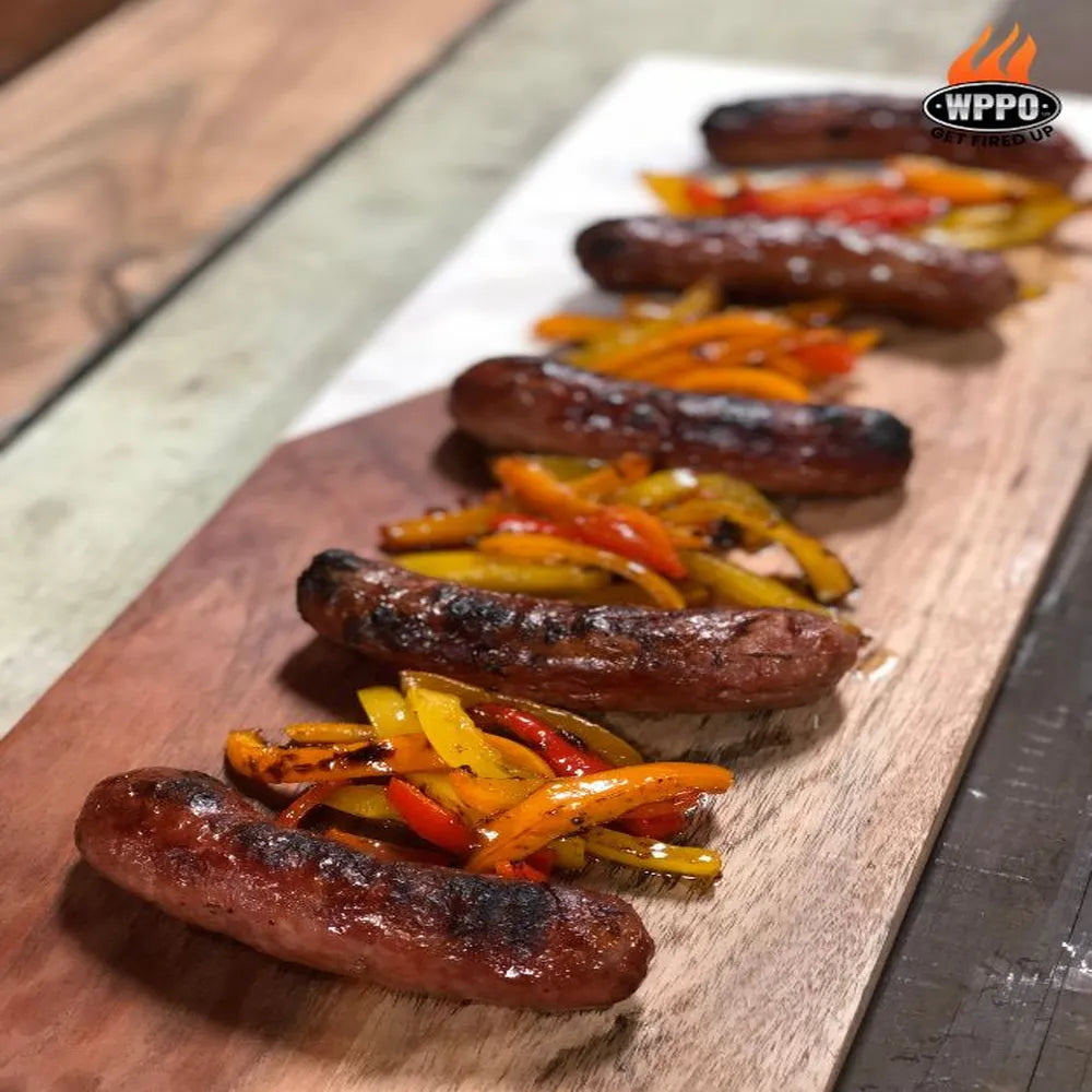 Grilled sausages and peppers cooked in WPPO Tuscany DIY wood-fired oven, served on a wooden board.