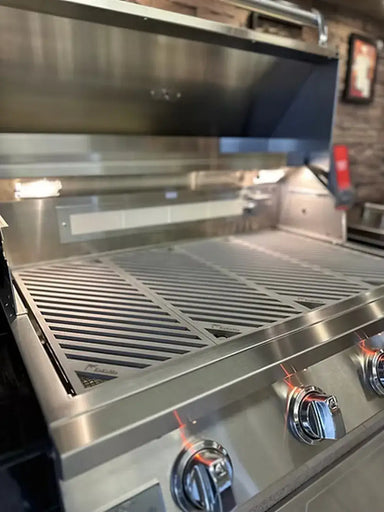 KoKoMo LuxCut laser-cut cooking grates installed in a stainless steel gas grill, viewed from the front with the hood open and interior lights on.