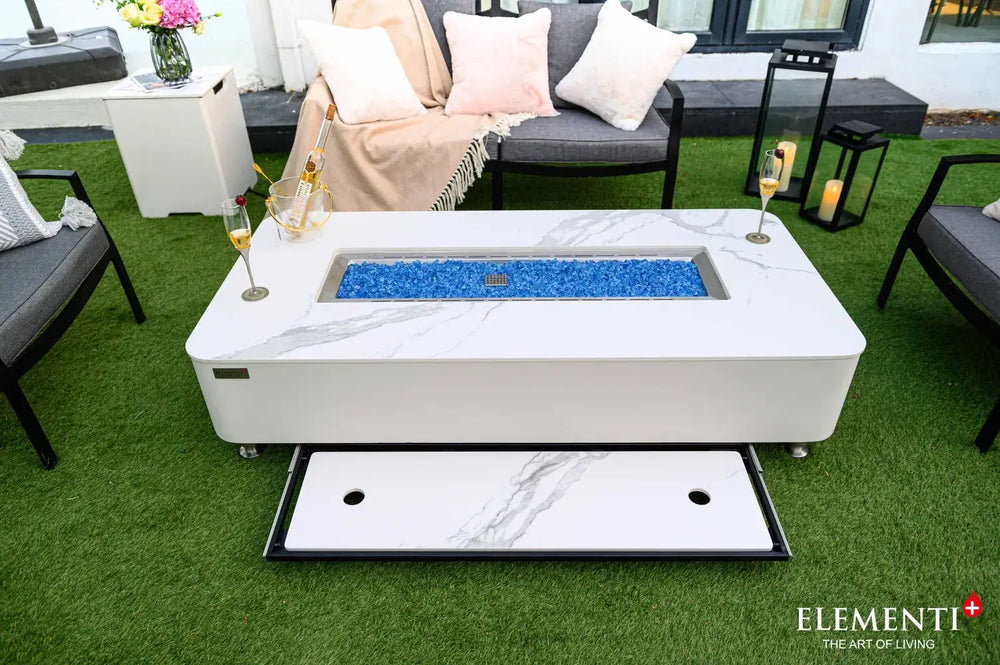 top-down view of the fire table on a patio, showing the matching marble-patterned lid stored in a sliding drawer that extends from underneath the table's main frame.