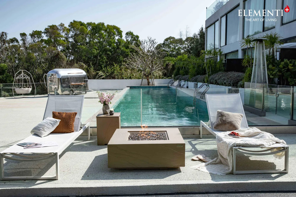 Elementi Plus OFG411SY Uluru sunlight yellow gas fire table on a luxury poolside patio.