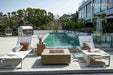 Elementi Plus OFG411SY Uluru sunlight yellow gas fire table on a luxury poolside patio.