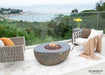 The Elementi Boulder fire table integrated into a modern balcony lounge area with a sweeping ocean view.