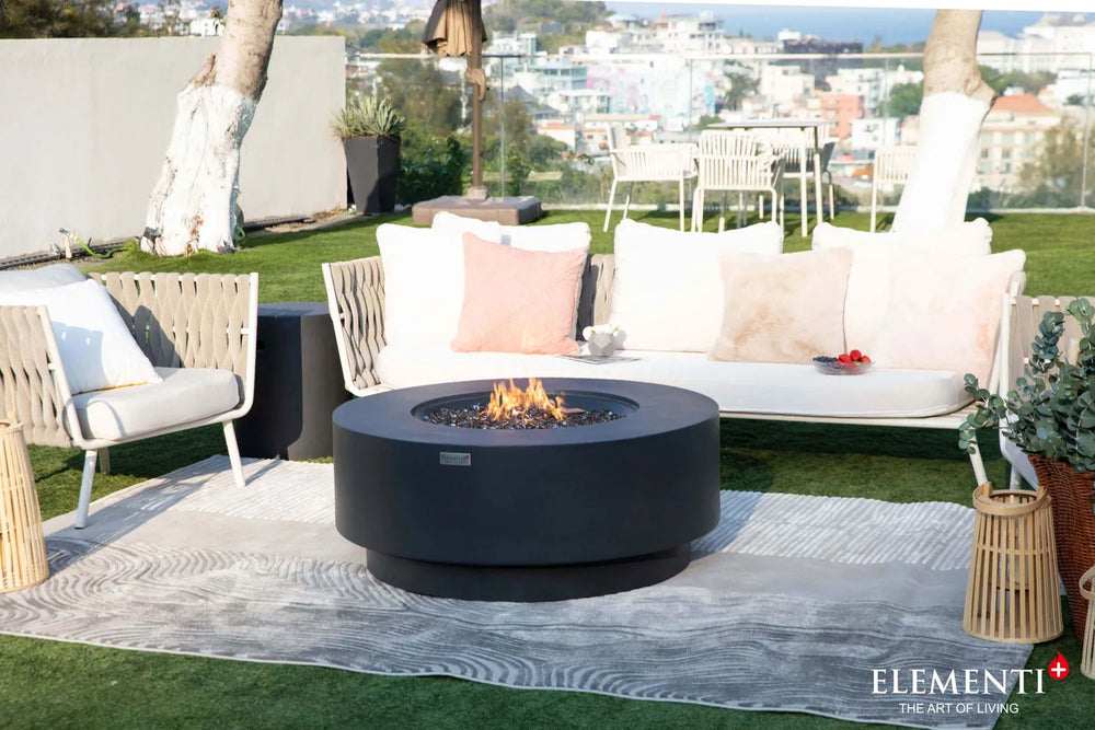 Elementi Plus Nimes dark gray round fire table on patio with modern outdoor seating.