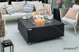 Close-up of the Bulgaria Black fire table’s linear burner, highlighting the clear glass wind guard and shimmering bronze fire glass under a warm flame.