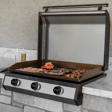 Blackstone built-in 36-inch outdoor gas griddle cooking steak, shrimp, and vegetables on stainless steel drop-in surface