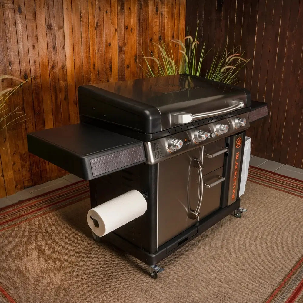 Blackstone 36-inch stainless steel griddle with hood, cabinet storage, and paper towel holder in backyard setup