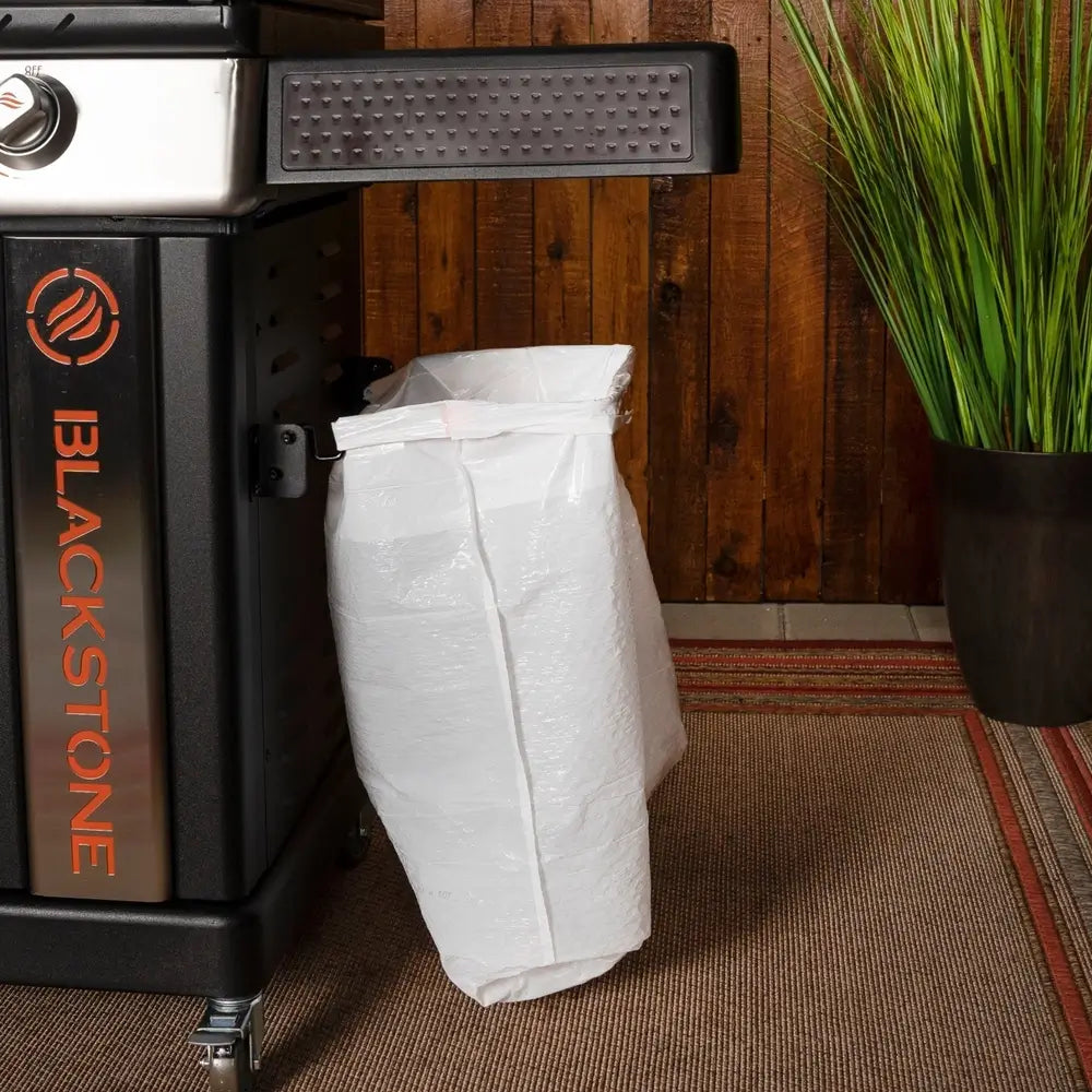 Side-mounted trash bag holder on Blackstone 36” griddle with cutting board pass-through system