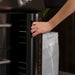 User opening side utility compartment on Blackstone 36" stainless steel griddle for tool storage