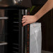 User opening side utility compartment on Blackstone 36" stainless steel griddle for tool storage