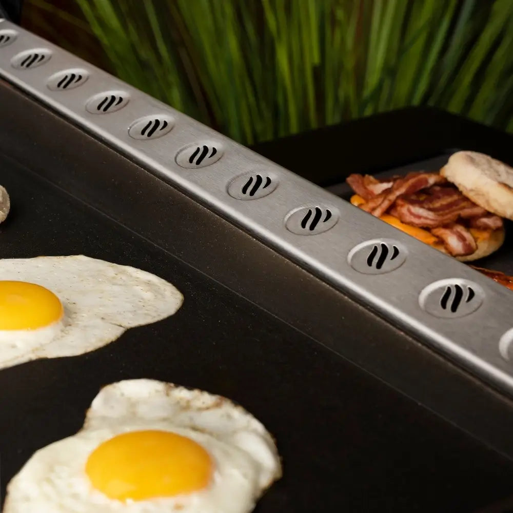 Eggs, bacon, and breakfast cooking on Blackstone 36-inch griddle with patented heat baffle vents