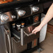 Hand opening drawer of Blackstone griddle cabinet revealing seasoning jars and stainless finish