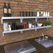 Sunstone SCC30KB-WLSHELF stainless wall shelves installed on brick outdoor kitchen wall, organized storage above sink and prep area.