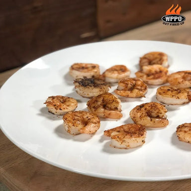Fresh shrimp seasoned with herbs cooking in a cast iron skillet inside a WPPO Lava 40 wood-fired oven.