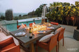 Elementi OFG201 Sonoma Dining Fire Table 45k BTU as a centerpiece on a luxury stone patio with greenery.