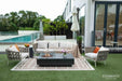 Elementi Metropolis fire table in a luxury seaside lounge setting with colorful pillows and a circular glass wind guard.