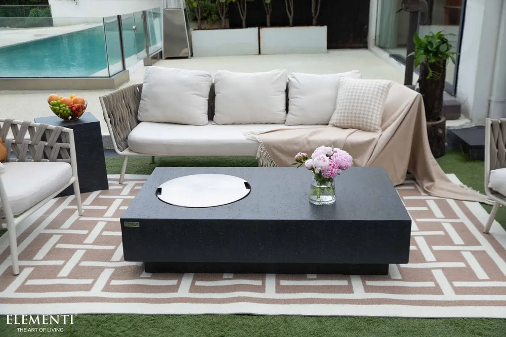 The Metropolis fire table used as a functional outdoor coffee table with a stainless steel lid and afternoon tea service.