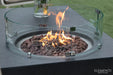 Close-up of the Metropolis fire table’s circular burner basin filled with natural lava rocks and a curved glass wind guard.