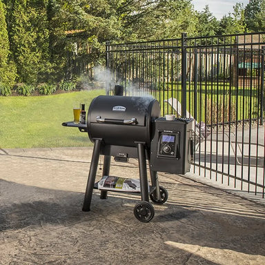 Broil King Regal Pellet 400 WiFi pellet grill, black freestanding smoker with digital control panel, side shelf, storage shelf, and wheeled base on an outdoor patio