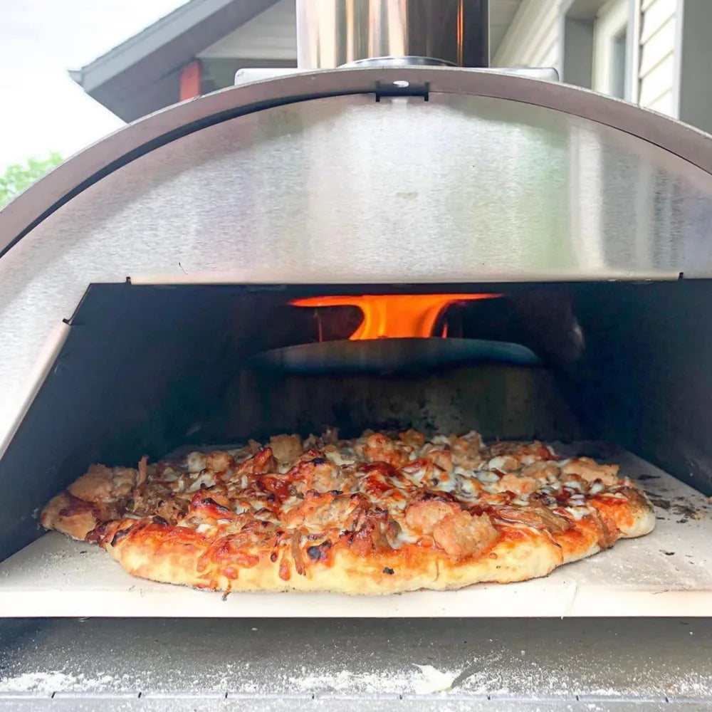 Pizza baking inside WPPO Lil Luigi portable wood-fired oven with open flame, stone cooking deck, and crisp crust.