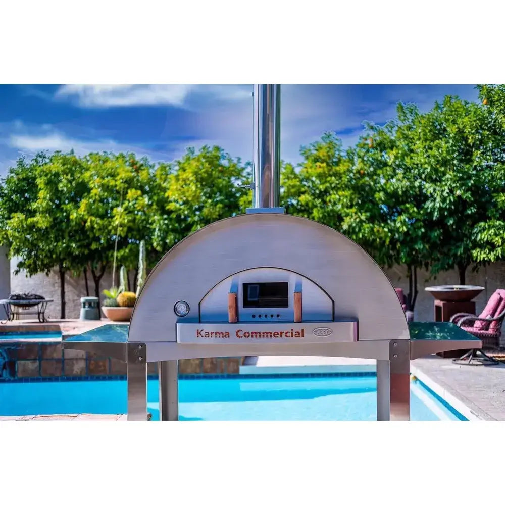 WPPO Karma 55 commercial wood-fired oven front view by pool with stainless steel dome, chimney, thermometer, and oven door.