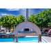 WPPO Karma 55 commercial wood-fired oven front view by pool with stainless steel dome, chimney, thermometer, and oven door.