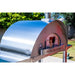 Angled view of WPPO Karma 55 commercial wood-fired oven with brushed stainless steel dome, chimney, and front door.