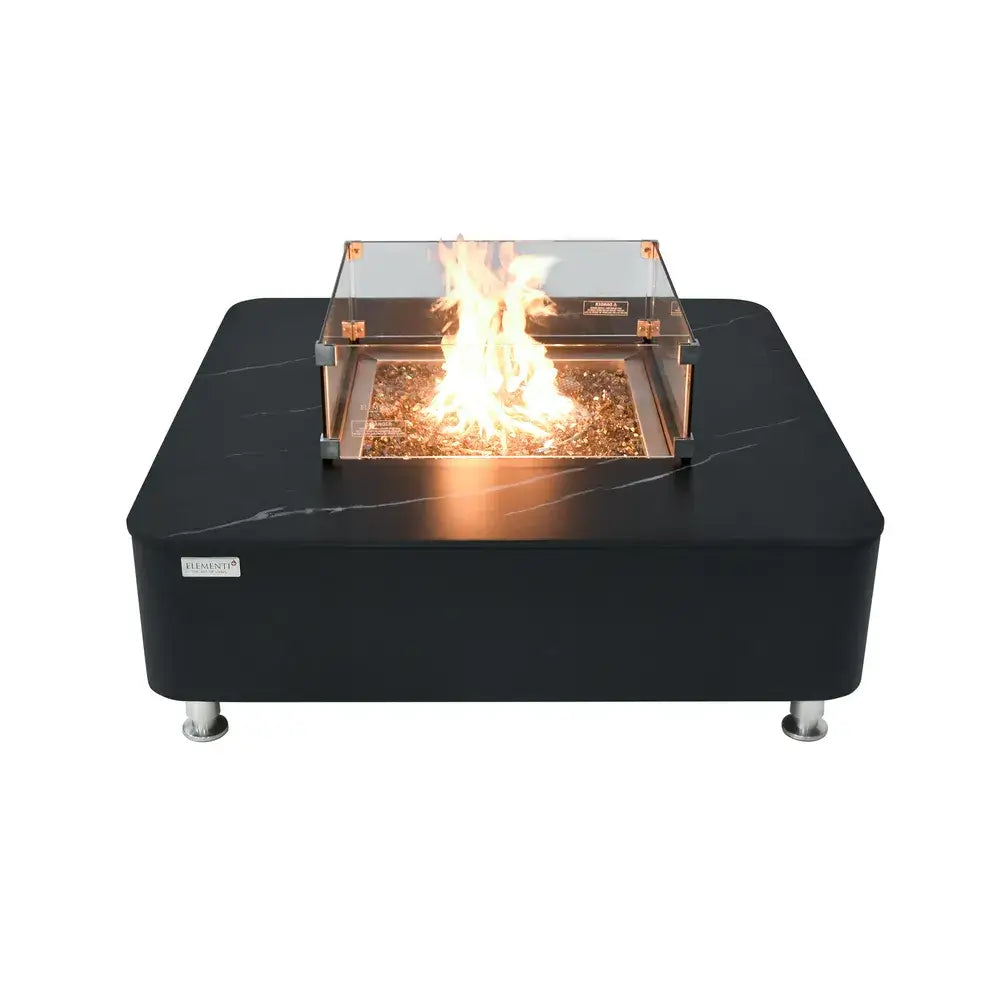 Black porcelain Elementi fire table featuring a square glass wind guard and central burning flame.