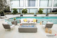 Elementi Plus OFG410SG Meteora 60,000 BTU fire table with a handcrafted slate grey concrete finish, styled on a luxury poolside patio with modern white lounge seating.