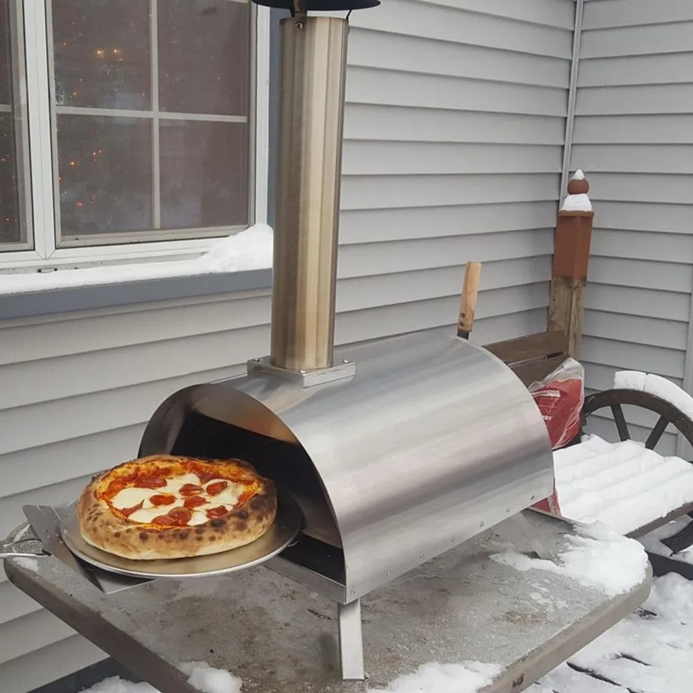 WPPO Lil Luigi portable stainless steel wood-fired pizza oven on outdoor snowy patio with pizza peel and chimney.