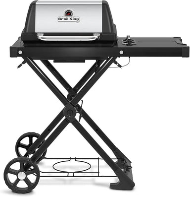 Front view of the Broil King Porta-Chef AT220 portable gas grill with stainless steel hood, black frame, folding scissor-style stand, right side shelf, and lower wire rack for propane storage.