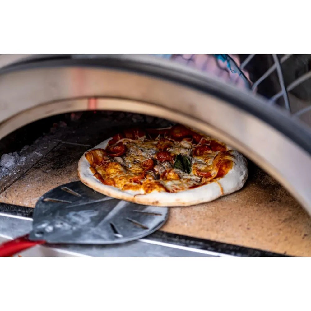 WPPO Karma 25 wood-fired oven cooking pepperoni pizza on a stone hearth with a metal pizza peel.