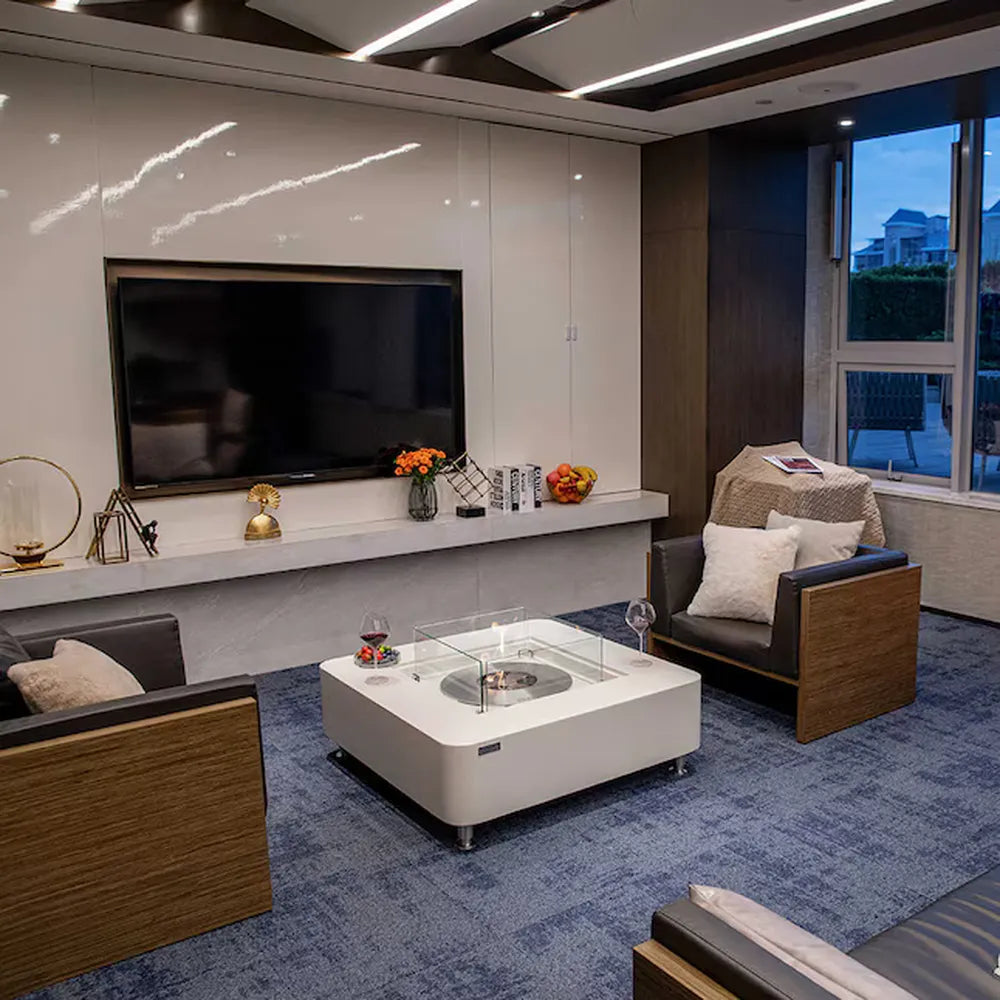 Lit Elementi ECG02CW Perth Ethanol Fire Table 43k BTU on a coastal infinity pool terrace at dusk.