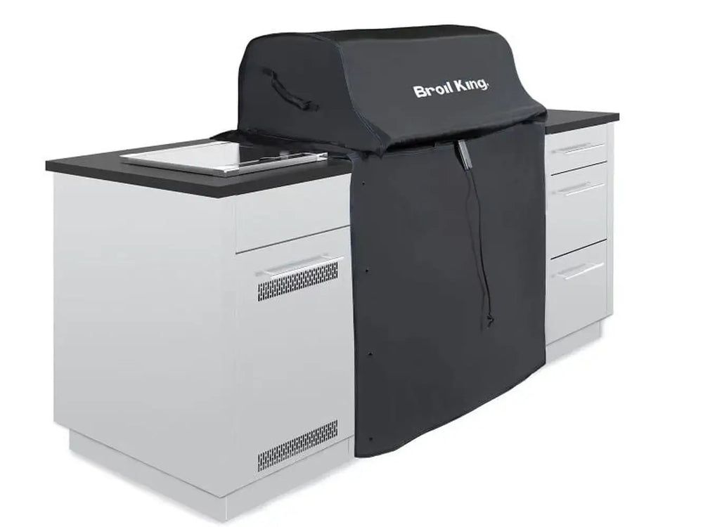 Broil King 68590 grill cover for 600 Series, shown over a grill in a white outdoor kitchen setup.