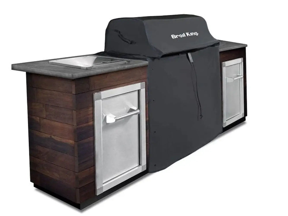 Broil King 68590 grill cover for 600 Series protecting a built-in grill in a wood-style outdoor kitchen island.