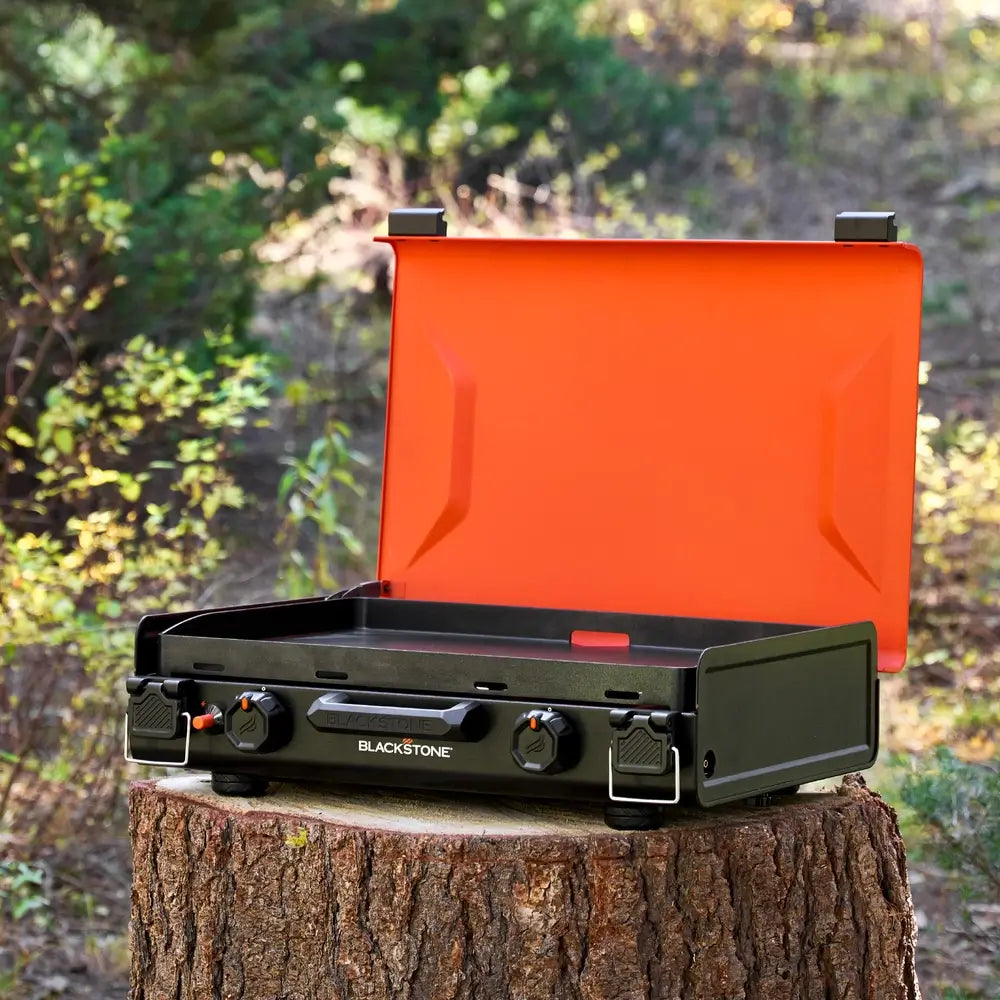 Angled front view of the Blackstone 20"x14" camping griddle with open lid, dual burners, and rugged outdoor-ready design.
