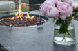 Modern outdoor living space featuring the 56-inch Metropolis fire table equipped with a protective circular glass wind guard.