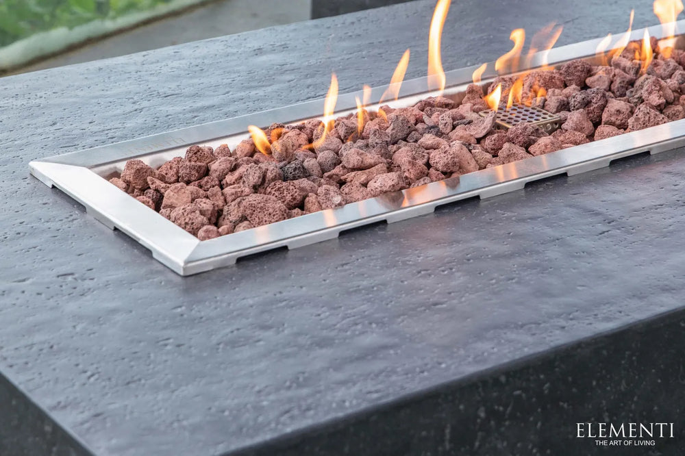 High angle view of a lit Elementi Hampton OFG139DG 56" Dark Gray Fire Table on a modern rooftop patio.