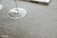 Close-up of the Elementi brand logo on the dark gray concrete-style finish of the Hampton OFG139DG Fire Table.