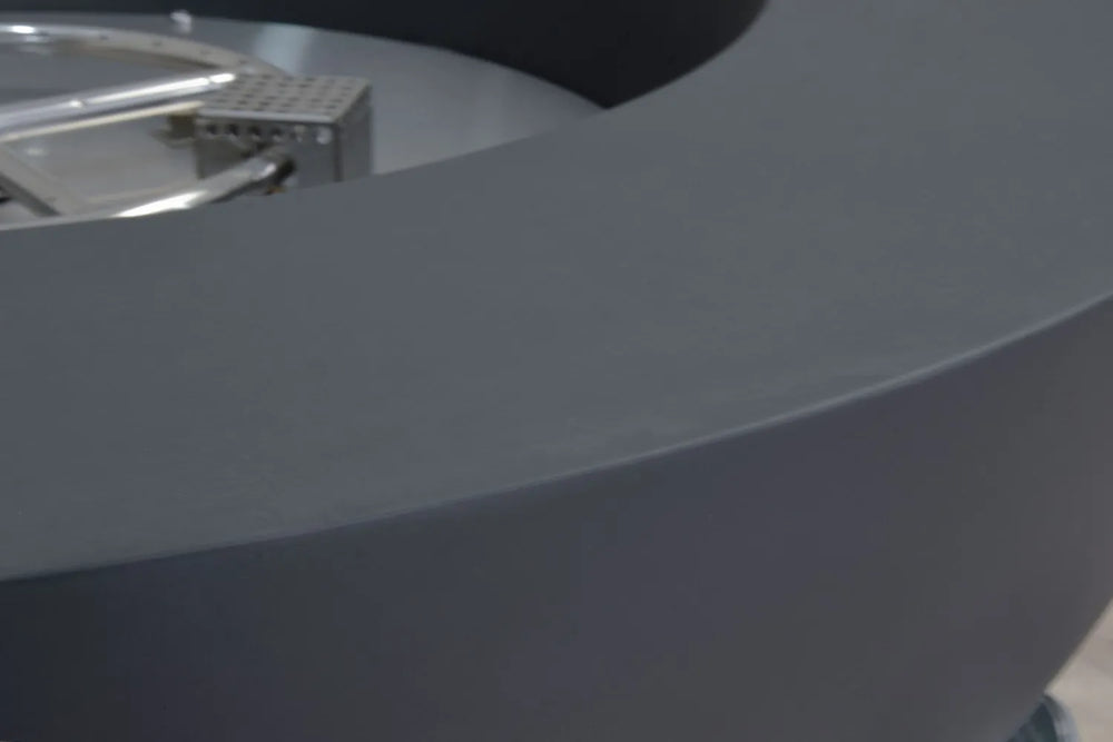 Close-up of the Elementi: The Art of Living silver logo plate on the side of a textured gray concrete fire pit.