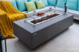 Angled view of Elementi Granville OFG121LG Fire Table with glass wind guard, wine, and appetizers.