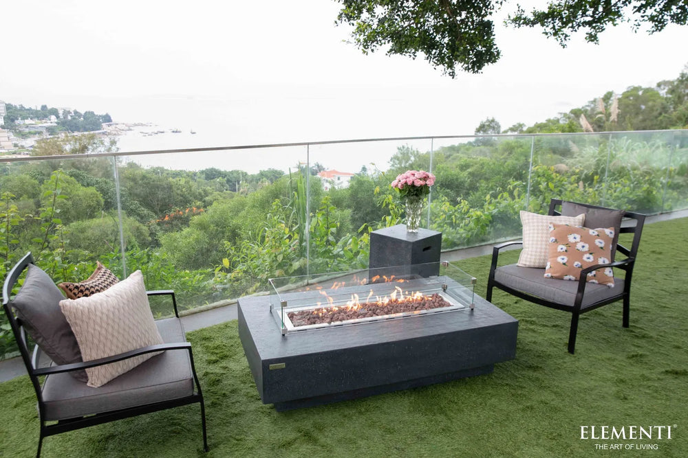 Beachfront patio featuring a lit Elementi Hampton OFG139DG Fire Table 56" Dark Gray with ocean views.