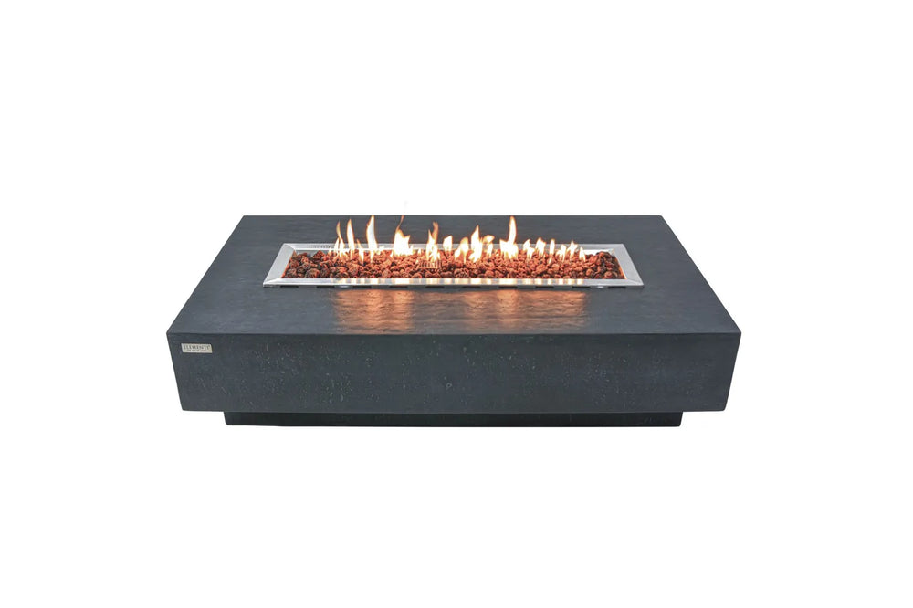 Lit Elementi Hampton OFG139DG Fire Table 56" Dark Gray with glass wind guard and lava rocks on white.
