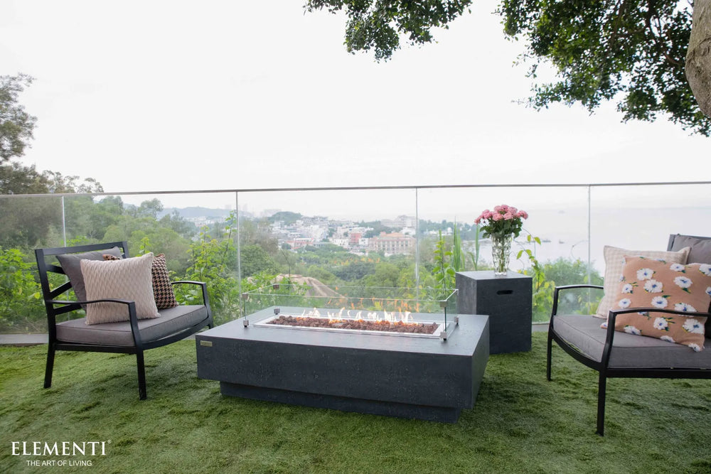 Unlit Elementi Hampton OFG139DG Fire Table 56" Dark Gray featuring a clear glass wind guard accessory.