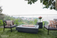 Unlit Elementi Hampton OFG139DG Fire Table 56" Dark Gray featuring a clear glass wind guard accessory.