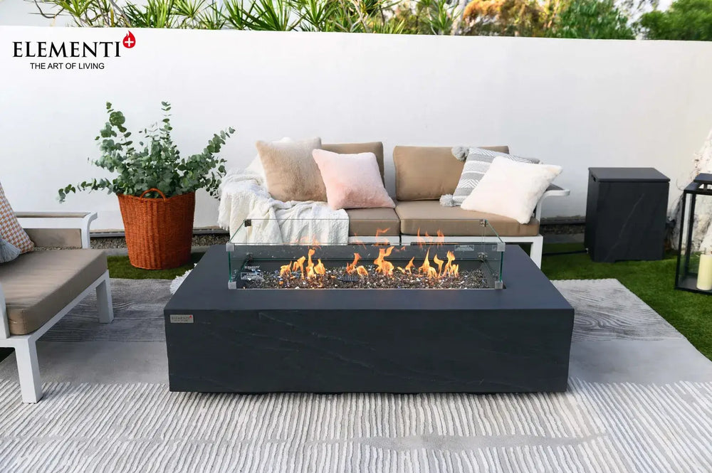 Elementi Plus OFG410SL Cape Town 60,000 BTU fire table with a handcrafted slate black stone finish, styled on a luxury poolside patio with white modern lounge chairs.